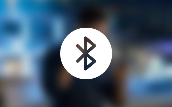 Значок Bluetooth на размытом фоне с изображением человека в наушниках, символизирующий беспроводное соединение.