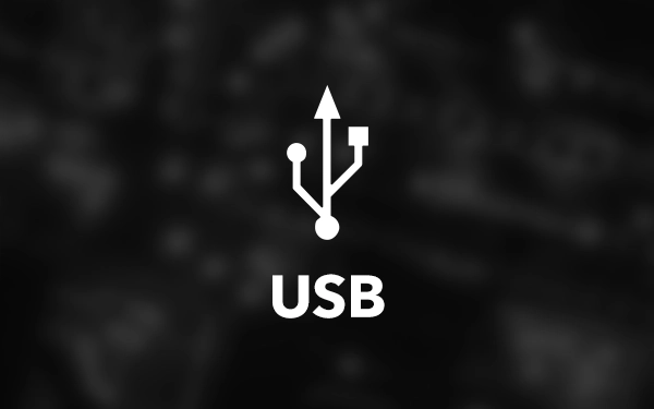 Білий логотип USB (універсальна послідовна шина) – символ з трьома кінцями над словом USB, на темному розмитому фоні
