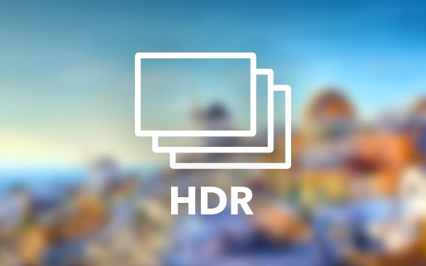 Білий логотип HDR (розширений динамічний діапазон) з трьома екранами, що перекриваються, на розмитому, барвистому пейзажному фоні